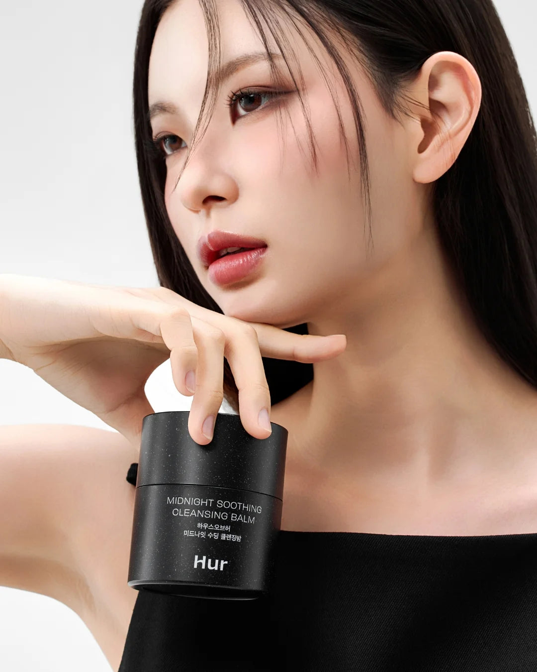 Vrouw houdt de House of Hur Midnight Soothing Cleansing Balm met grinder-verpakking vast