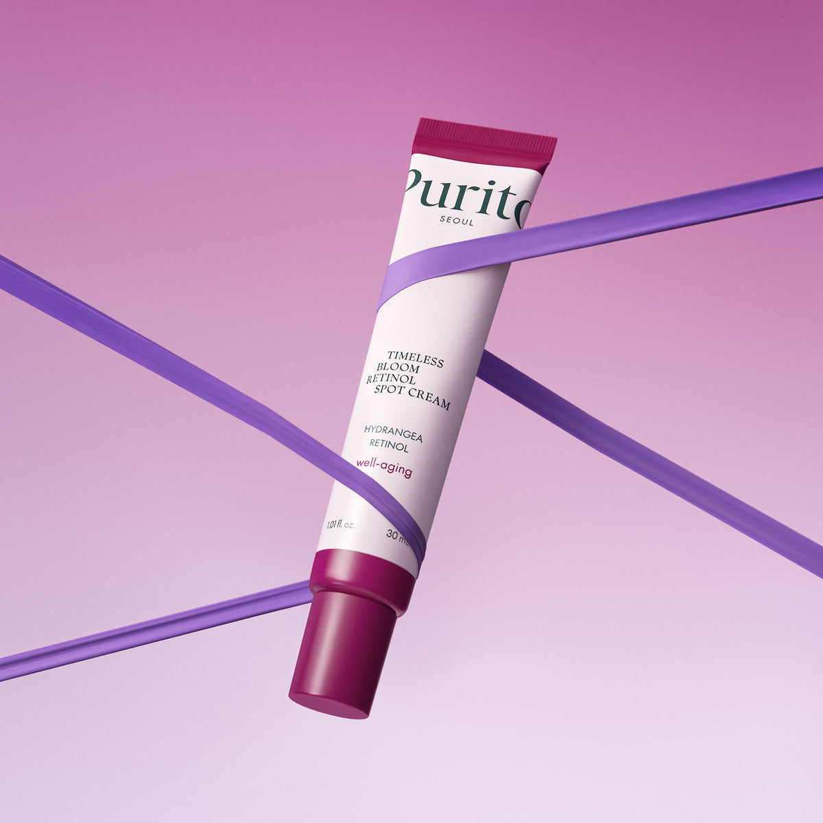 PURITO Timeless Bloom Retinol Spot Cream 30ml, tube op paarse achtergrond met linten