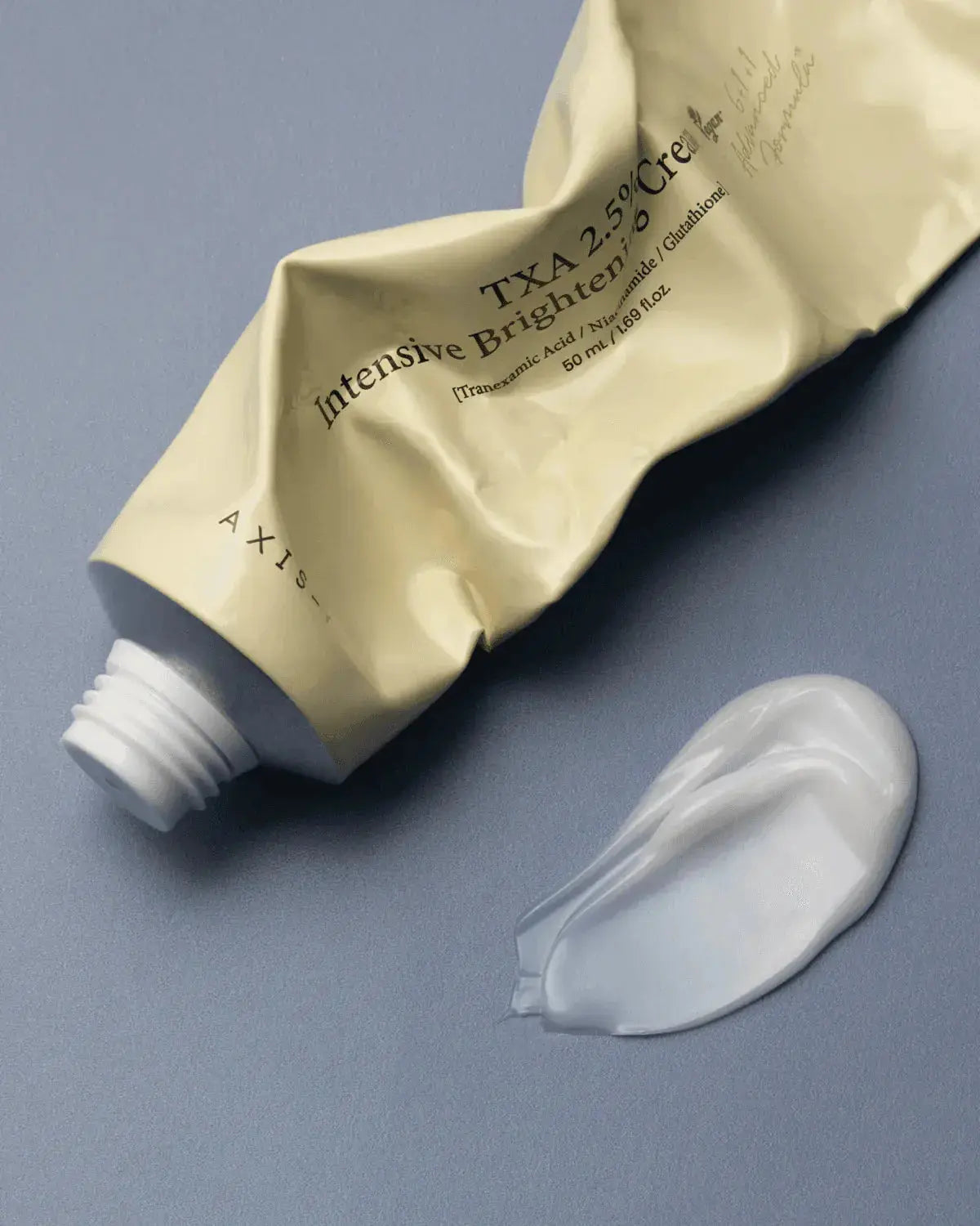 AXIS-Y TXA 2.5% Intensive Brightening Cream, opgerolde tube met een veeg crème