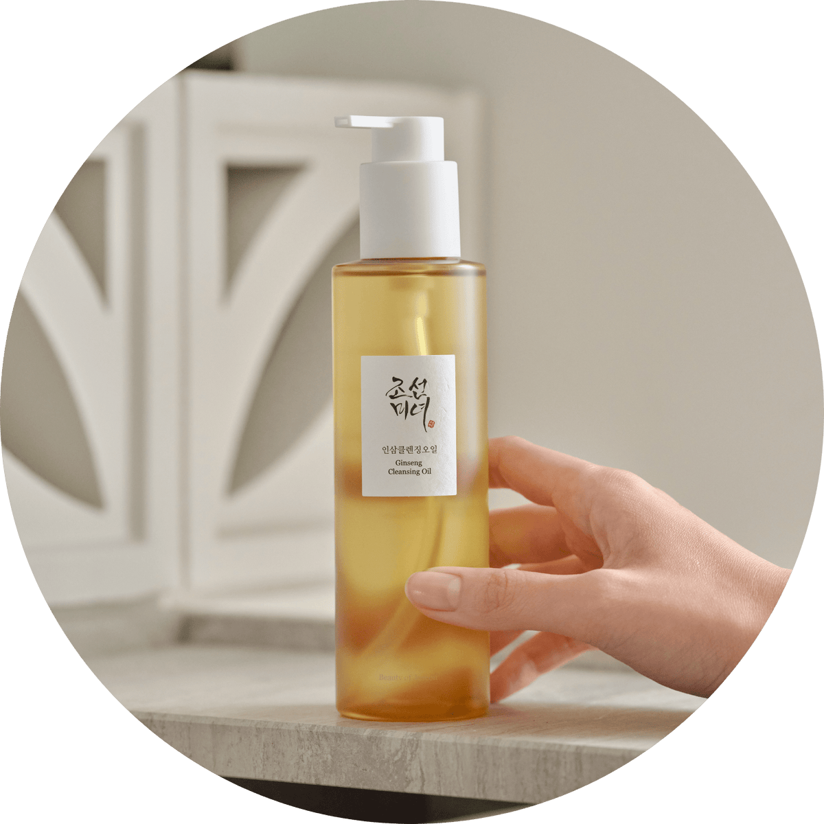 Hand houdt de flacon Beauty of Joseon Ginseng Cleansing Oil 210ml vast