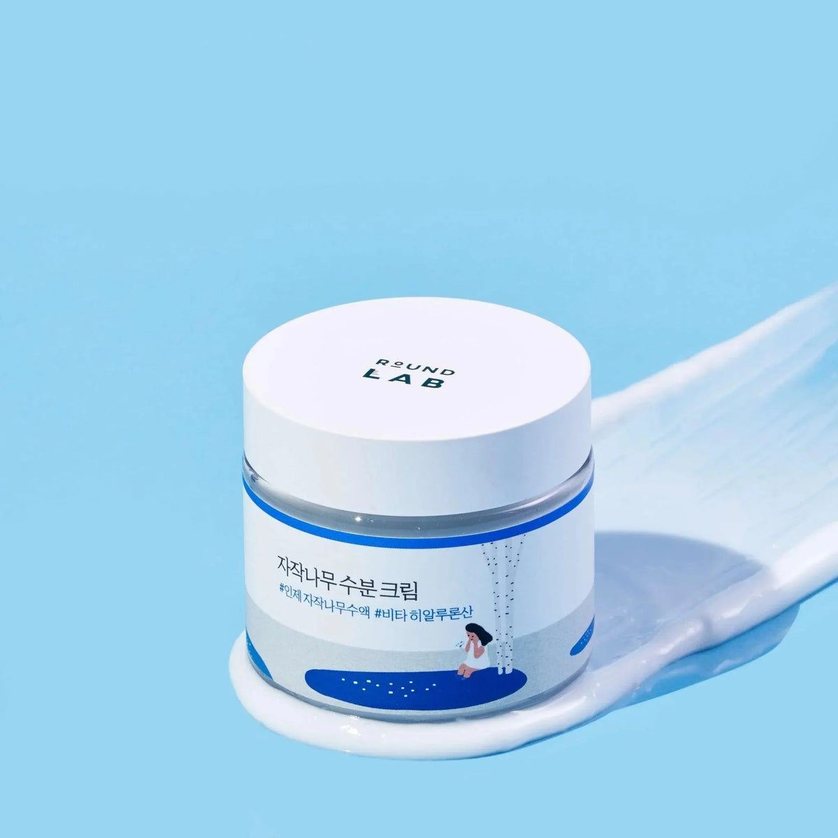 Round Lab Birch Juice Moisturizing Cream, pot met een veeg crème op blauw
