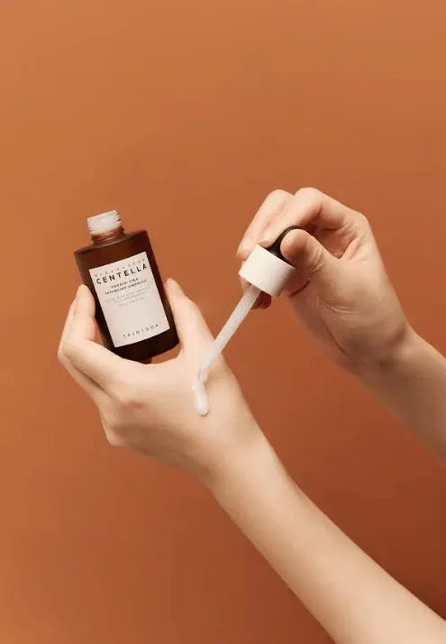 Handen halen de pipet uit de fles SKIN1004 Probio-Cica Intensive Ampoule