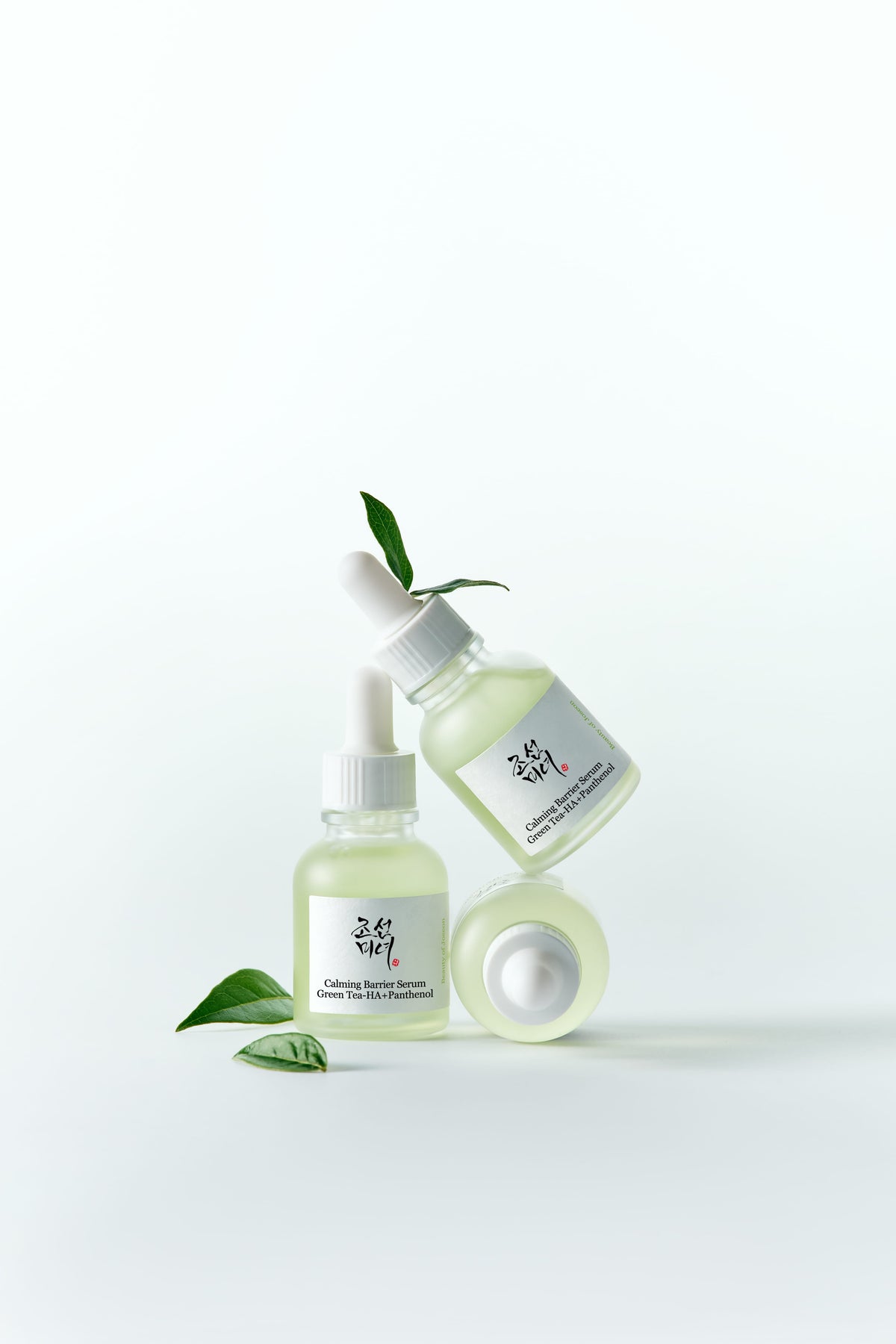 Twee flesjes Beauty of Joseon Calming Barrier Serum op elkaar gestapeld met groene blaadjes