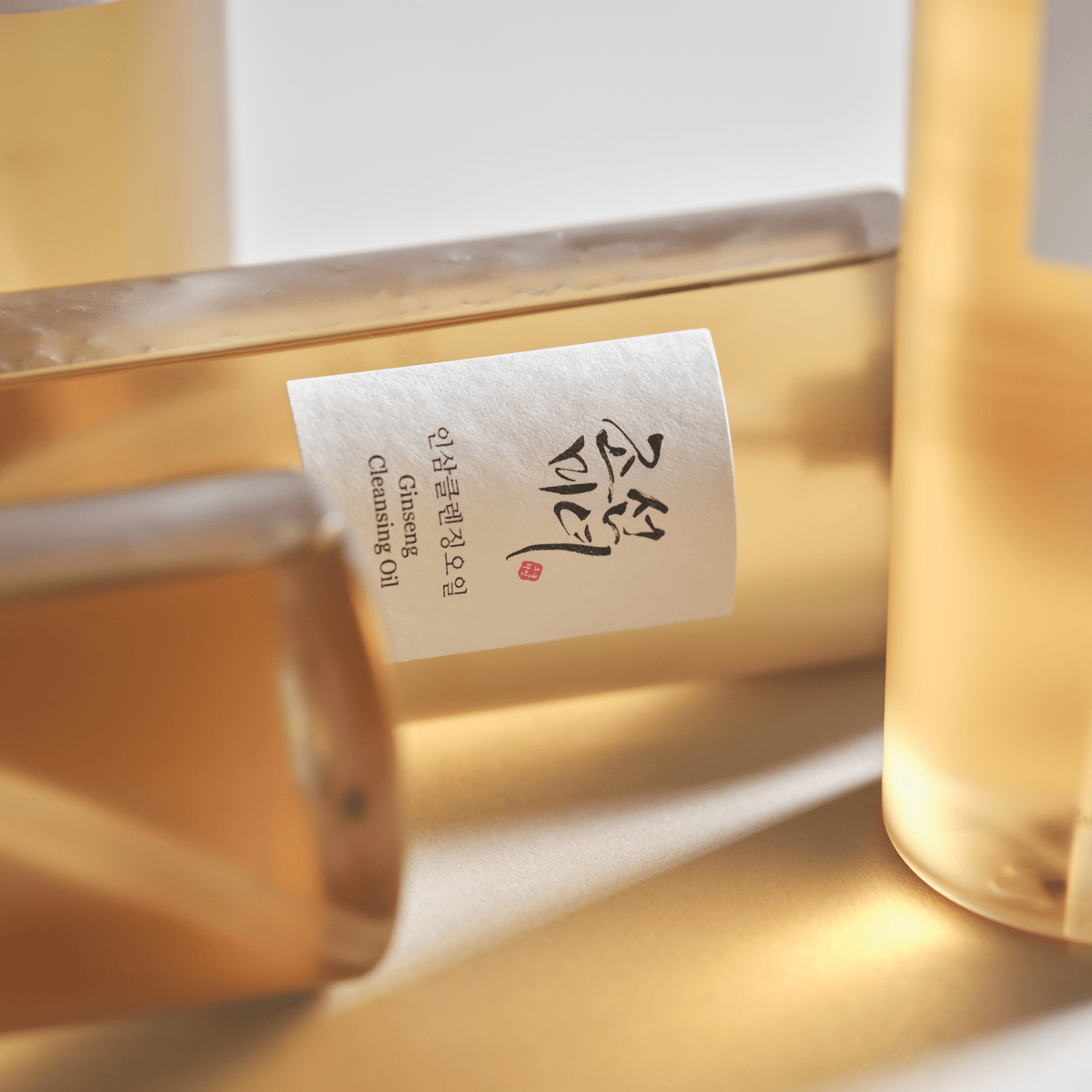 Flacon Beauty of Joseon Ginseng Cleansing Oil in warm licht met goudkleurige olie