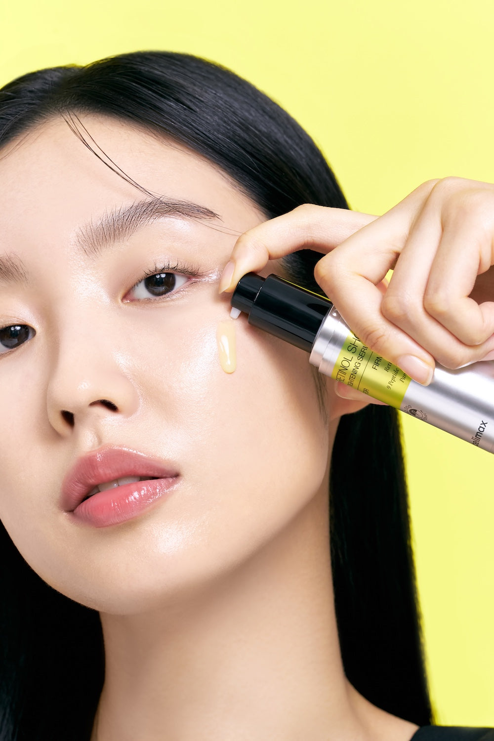 Model brengt het Celimax Retinol Shot Serum aan op de huid onder het oog