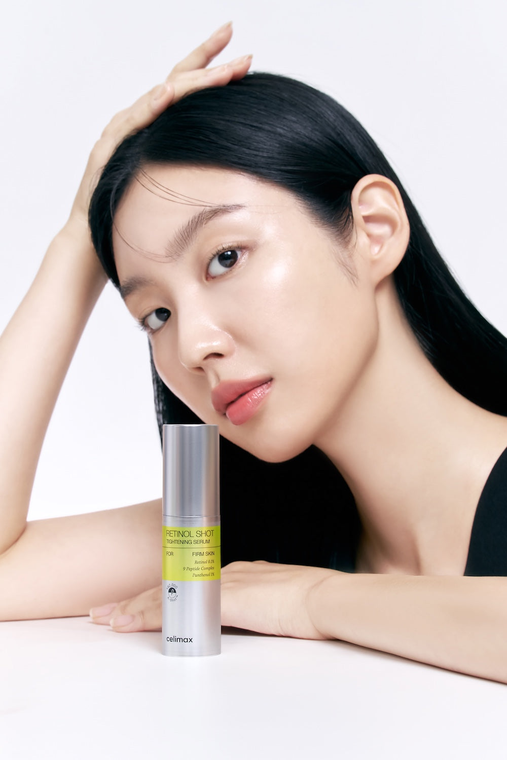 Model leunt naast een flesje Celimax Retinol Shot Tightening Serum