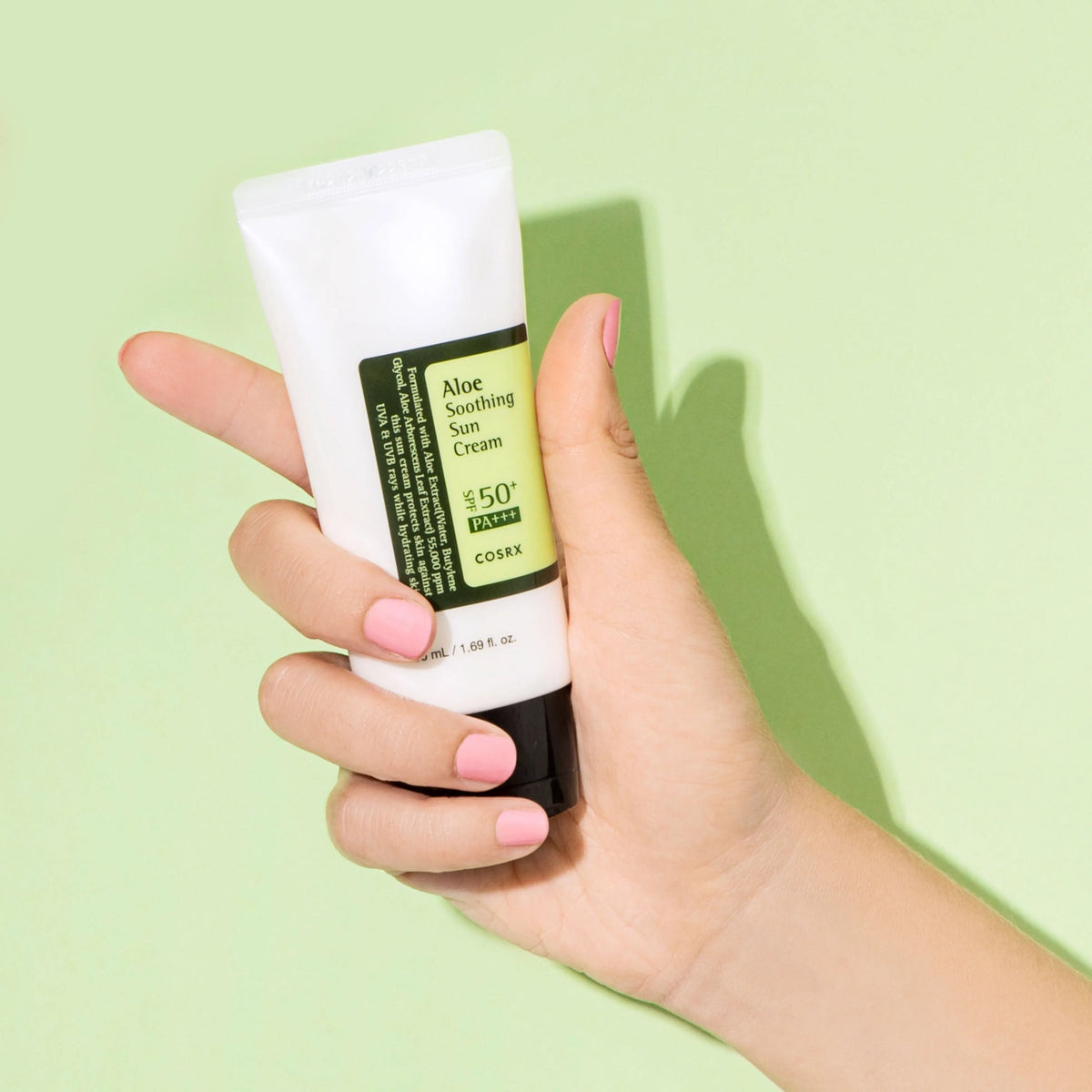COSRX Aloe Soothing Sun Cream SPF50+ PA+++ in de hand tegen een groene achtergrond