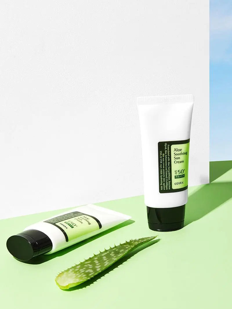 COSRX Aloe Soothing Sun Cream SPF50+ PA+++, twee tubes naast een aloë vera blad