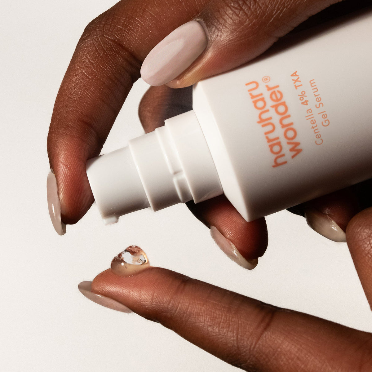 Druppel Haruharu Wonder 4% TXA Dark Spot Go Away Serum op vingertop, close-up van de pomp