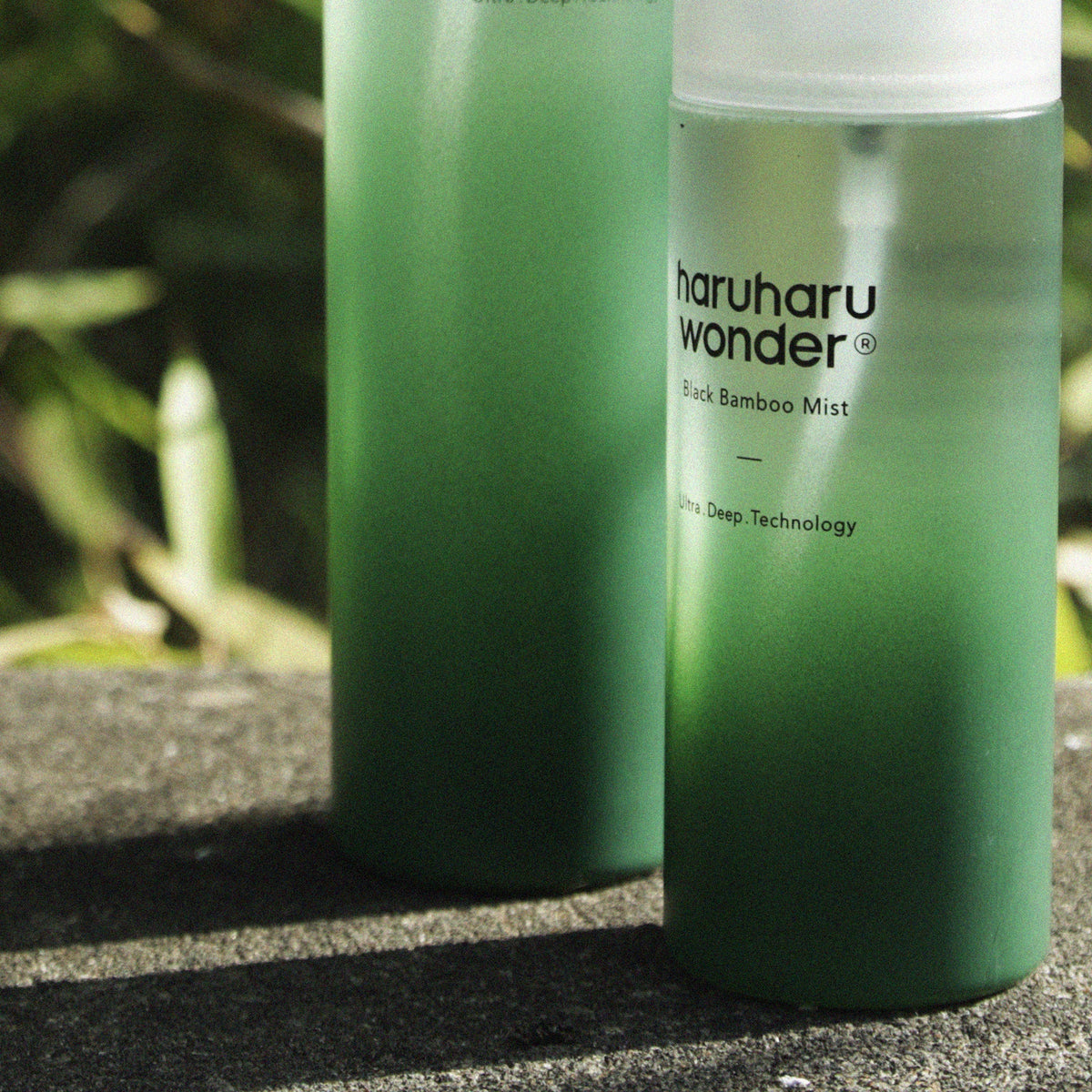 Twee flacons Haruharu Wonder Black Bamboo Mist Jumbo op een stenen rand in de zon