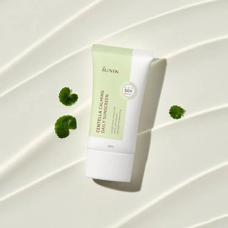 iUNIK Centella Calming Daily Sunscreen, tube op uitgestreken crème met centellablaadjes