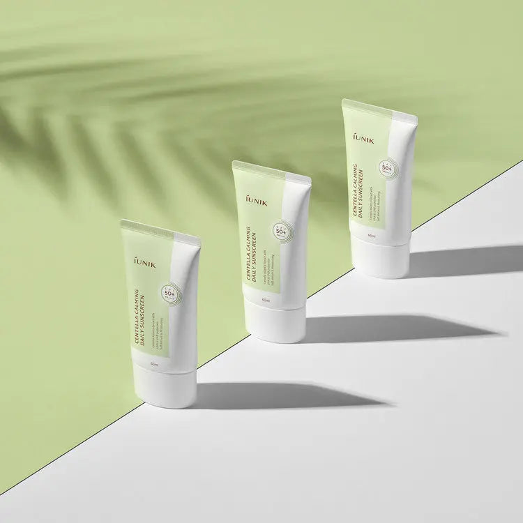 iUNIK Centella Calming Daily Sunscreen, drie tubes op een groene achtergrond