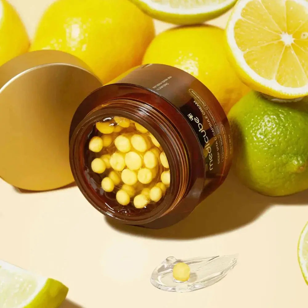 Medicube Deep Vita C Capsule Cream, geopende pot met gele capsules tussen citroenen en limoenen