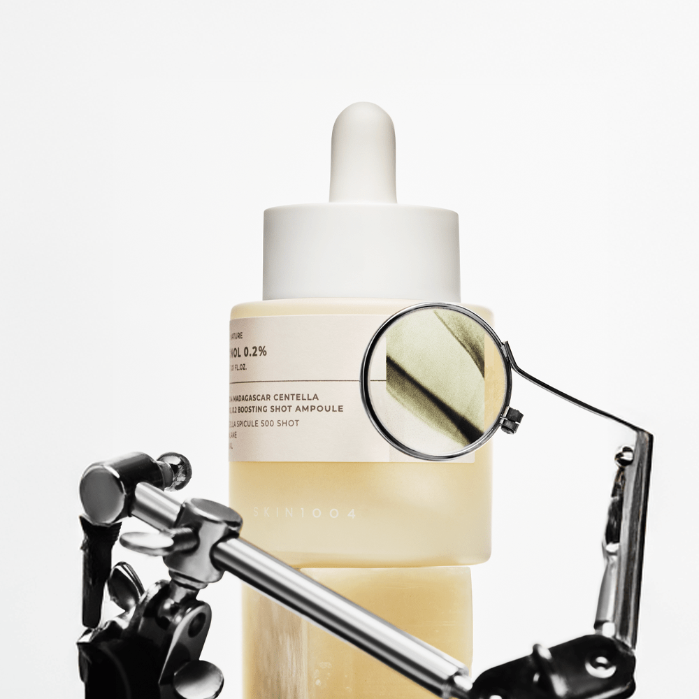 Close-up van de SKIN1004 Retinol 0.2 Boosting Shot Ampoule onder een vergrootglas