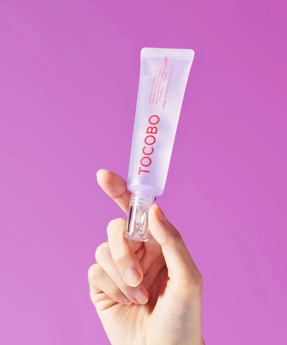 TOCOBO Collagen Brightening Eye Gel Cream, hand houdt de tube tegen een paarse achtergrond